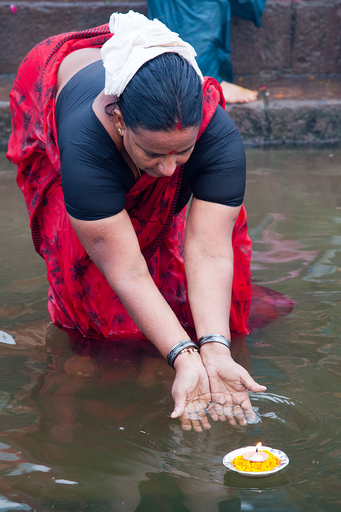 A woman launches an offering into the Ganges.
