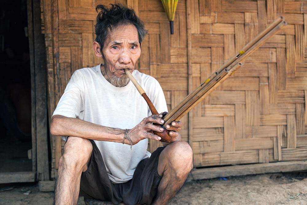 A Khou man, high on opium, playing a traditional instrument called a "Khen".