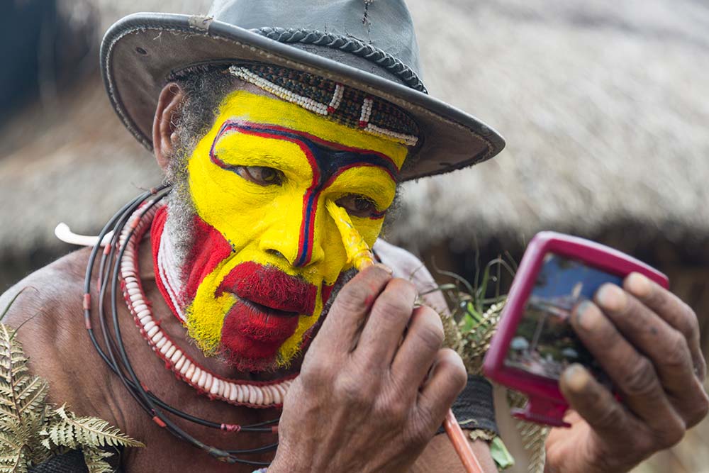 A Huli man paints his face in preparation for a Sing Sing.