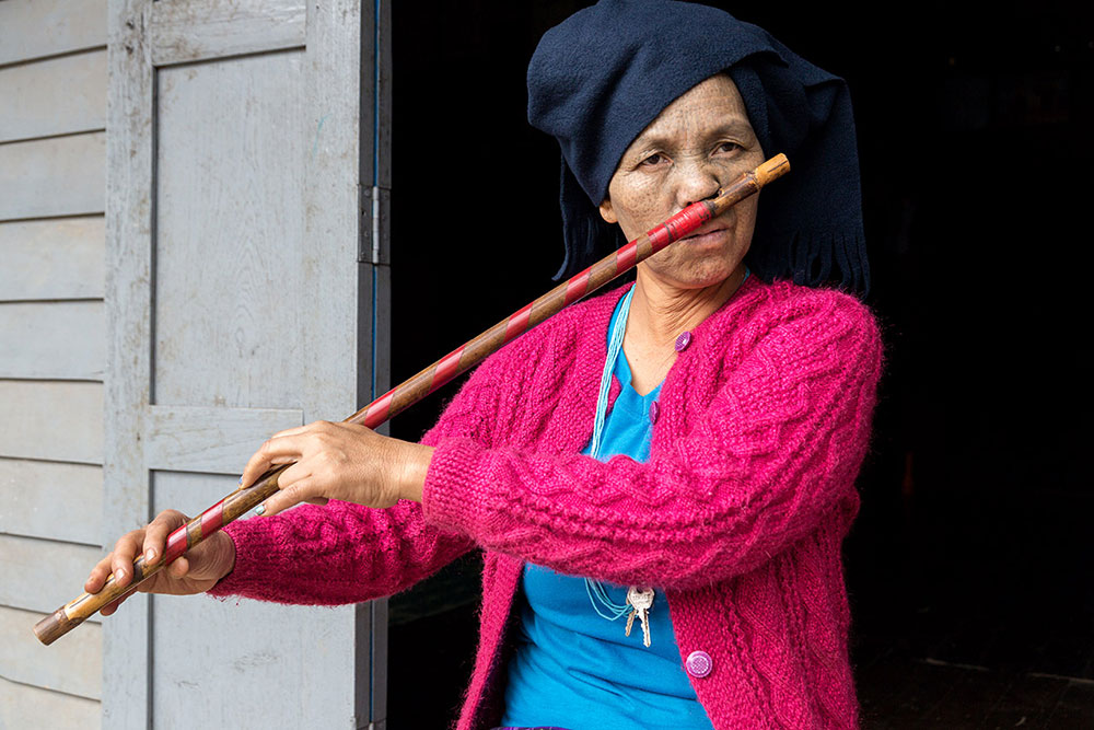 A Dai Chin woman playing traditional nose flute.